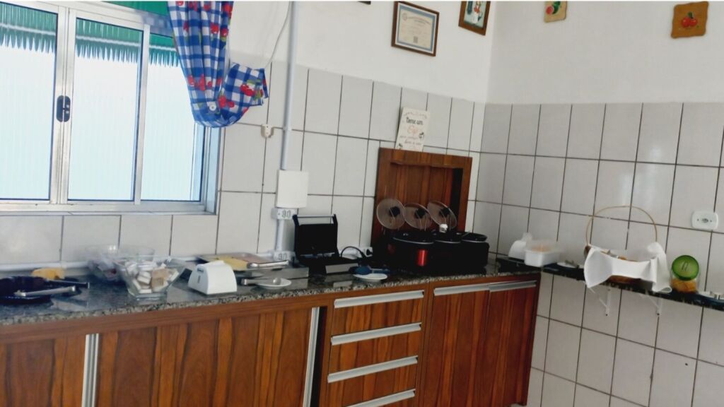 Balcão de cozinha com pães, frios e utensílios em um ambiente azulejado.