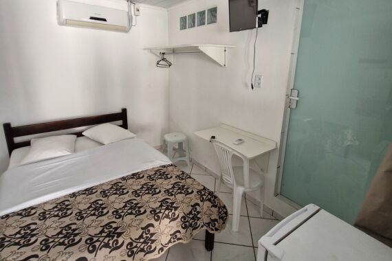 Quarto com cama de casal, mesa de trabalho e ar-condicionado.