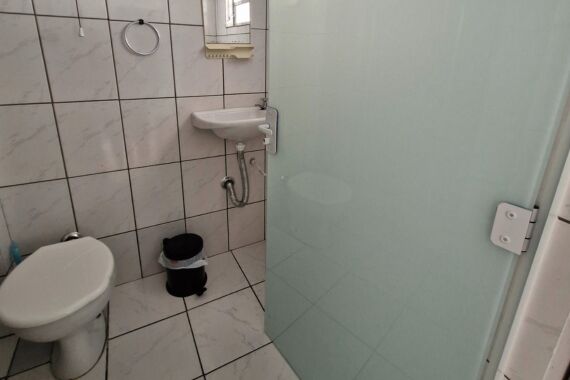 Entrada do banheiro com pia, espelho e vaso sanitário.