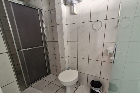 Vaso sanitário ao lado de box com porta de correr.