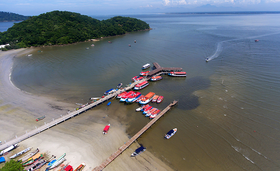 Trapiche com barcos coloridos ancorados na Ilha do Mel, cercado por mar calmo.